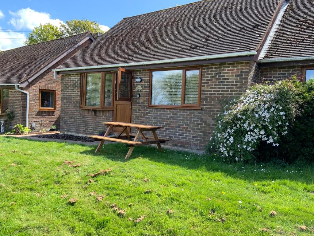 a wooden picnic table in front of a house at Daisy Cottage in Polegate