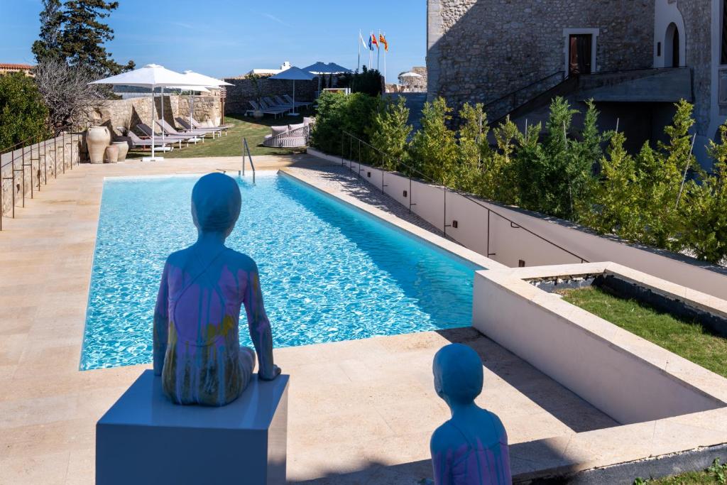 two statues sitting next to a swimming pool at Parador de Ibiza in Ibiza Town