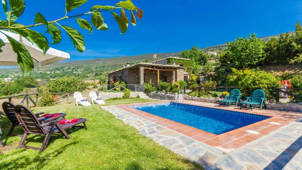 a backyard with a pool and chairs and a house at Cortijo Noguera La Taha - Pitres by Ruralidays in Granada