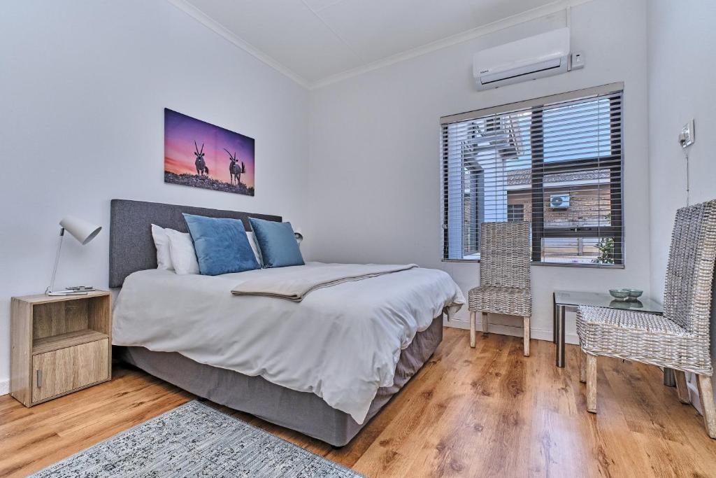 a bedroom with a bed and a desk and a window at 3 Kiaat Suites in Klerksdorp