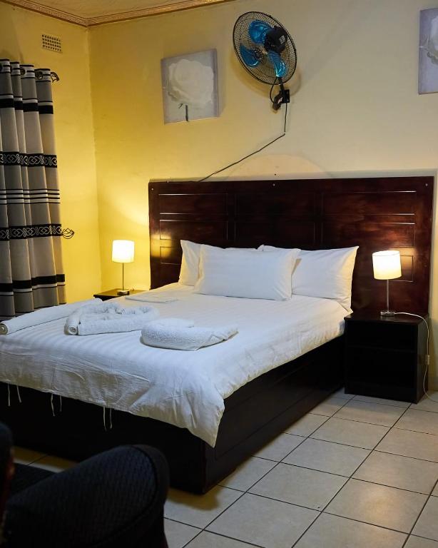 a bedroom with a large bed with white sheets and two lamps at Niyonest Guesthouse in Harare