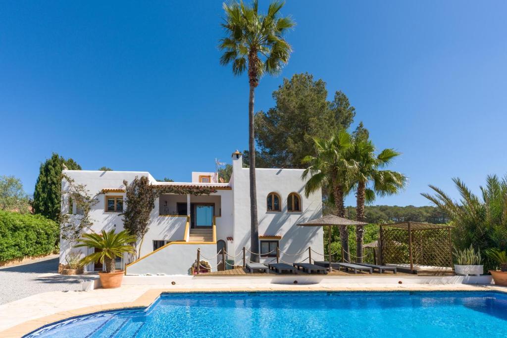 a villa with a swimming pool and palm trees at Asteria Eco Finca Sustainable 6 Bedroom Nature Retreat near UNVRS Ibiza in Santa Gertrudis de Fruitera