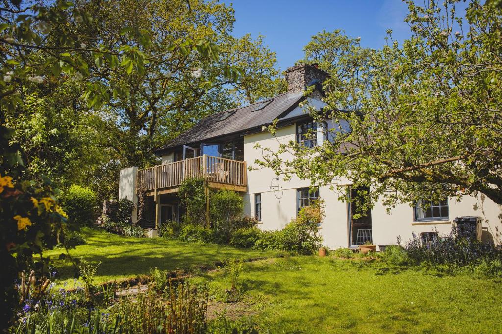 an old white house with a balcony on a lawn at Plasbach Cottage in Llandeilo