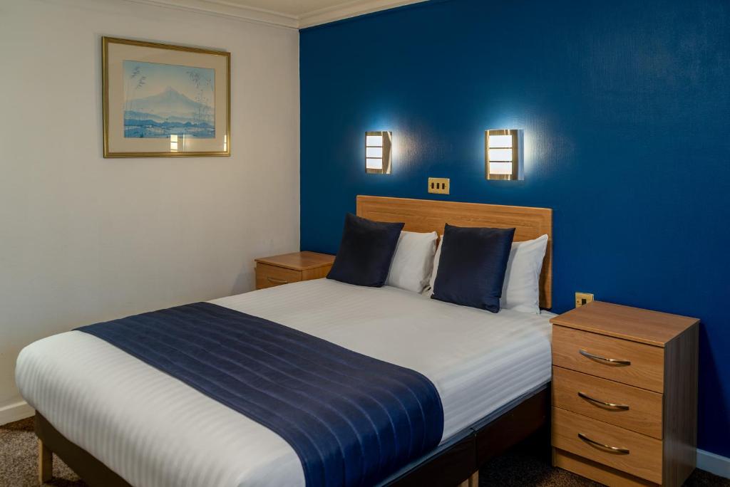 a bedroom with a bed with a blue wall at Britannia Hotel Coventry in Coventry