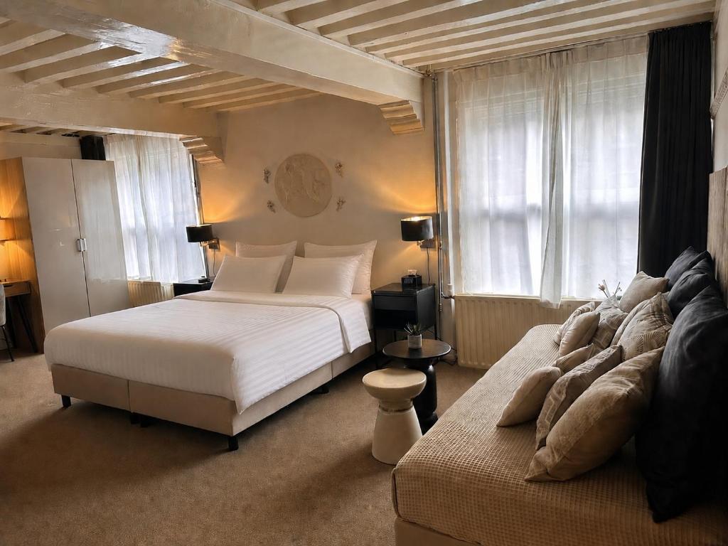 a bedroom with a large white bed and a couch at Grand Canal Boutique Hotel Delft in Delft