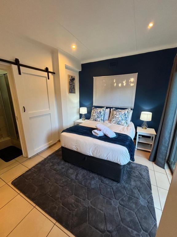 a bedroom with a bed with a blue wall at Cottage in Ballito in Ballito