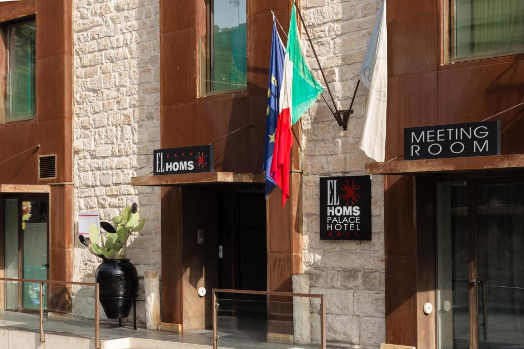 un edificio con una bandera a un lado. en El Homs Palace Hotel, en Comiso
