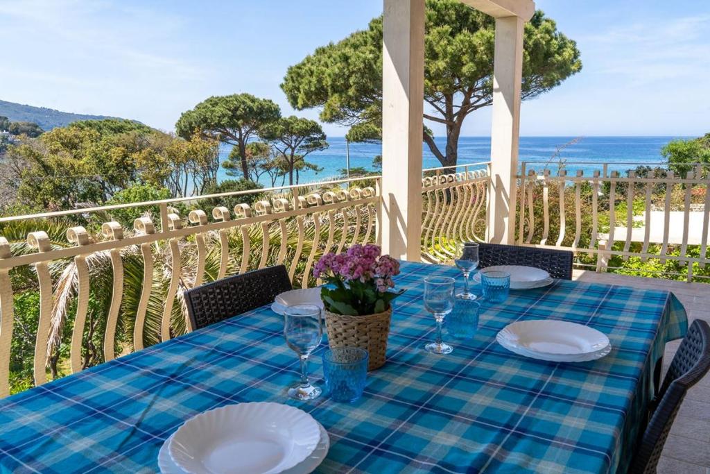 a table with plates and wine glasses on a porch at Appartamenti Procchio Onda e Marina - Tesi Viaggi in Procchio