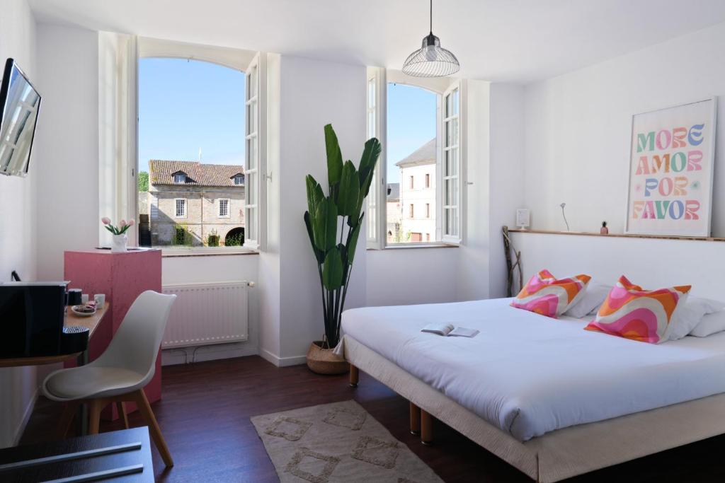 a bedroom with a bed and a table and two windows at Hôtel Restaurant Le Commerce in Navarrenx