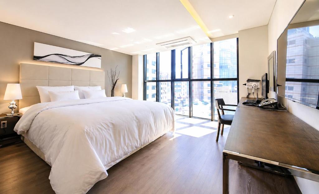 a bedroom with a large white bed and large windows at Seoul Ahava Hotel in Seoul