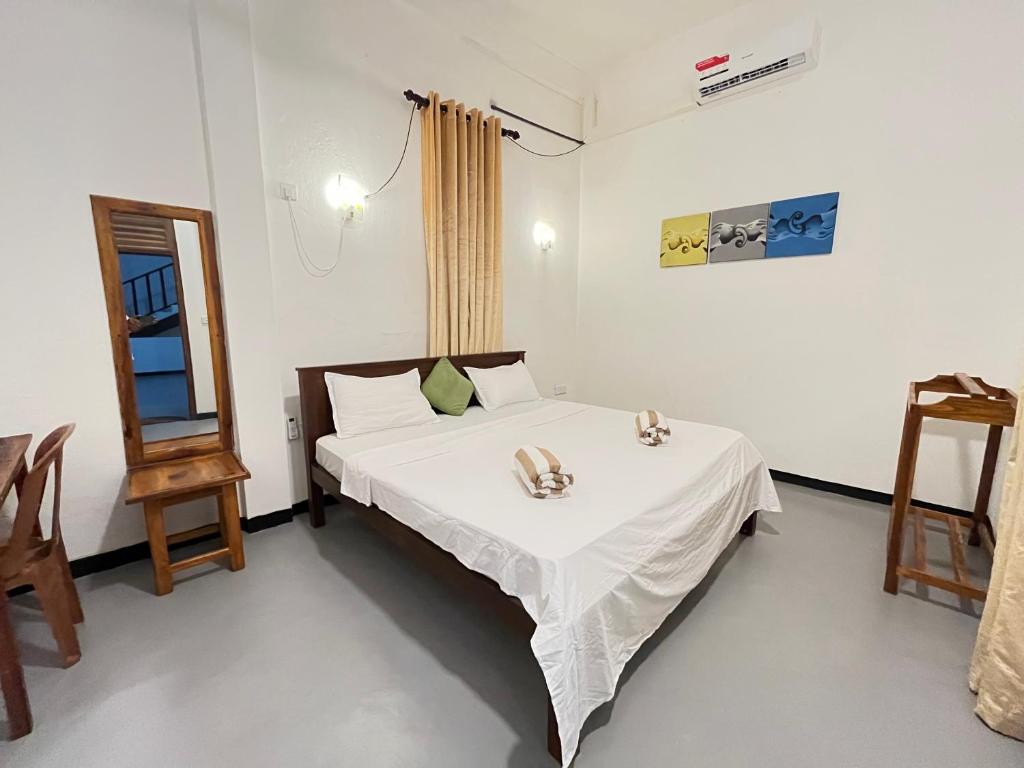 a bedroom with a bed with a table and a mirror at Lumieri Hotel Arugambay in Arugam Bay
