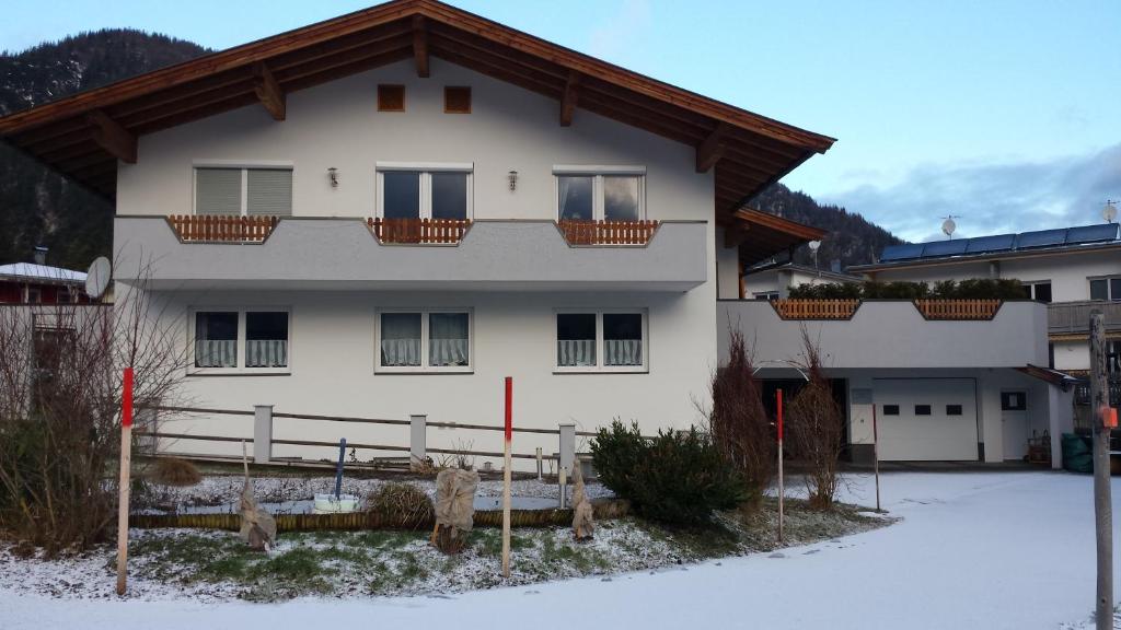 ein weißes Haus mit einem Holzzaun im Schnee in der Unterkunft Ferienwohnung Obermoser in Sankt Ulrich am Pillersee
