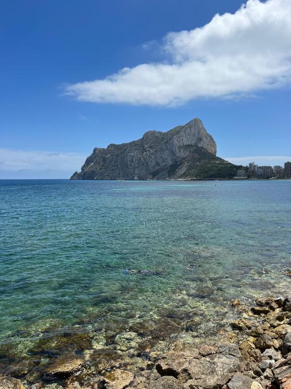 a large body of water with a mountain in the background at Oasis Mediterráneo in Ifach