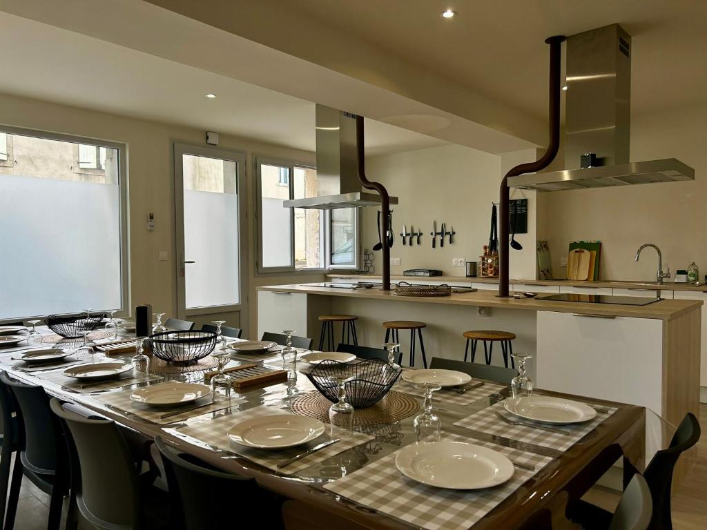 a long table with chairs and plates on it in a kitchen at L'Apparth, maison partagée 7 chambres in Parthenay