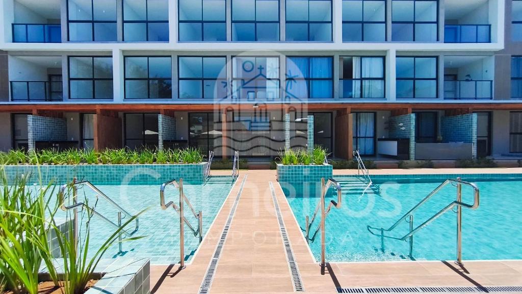 a swimming pool in front of a building at Acqua Beach Residence by CTA in Tamandaré