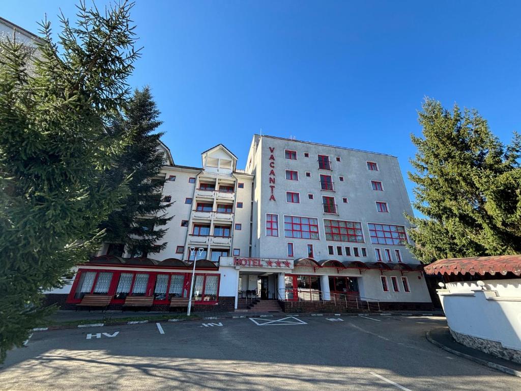 a tall white building with a street in front of it at Hotel Vacanța in Geoagiu Băi