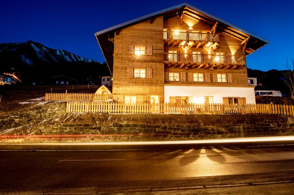 a large wooden building with lights on the side of a street at alpen select lodge Kleinwalsertal in Riezlern