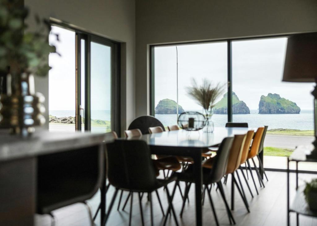 a dining room with a table and chairs with a view of the ocean at Luxury Ocean Villas in Vestmannaeyjar