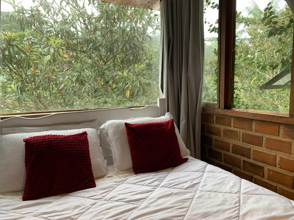 a bedroom with a bed with two pillows and a window at Chalé Vale do Amor in Araras Petropolis