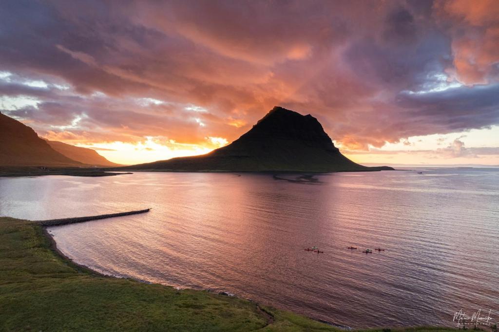 a sunset over a body of water with a mountain at Hafnir in Grundarfjordur