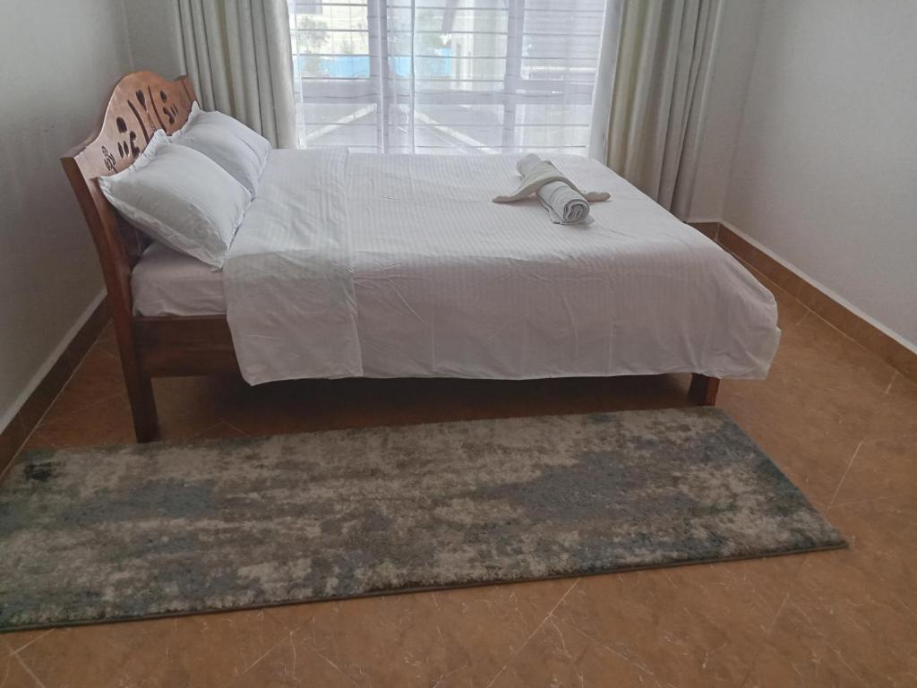 a bedroom with a bed and a chair and a window at Karani Suites in Nyahururu