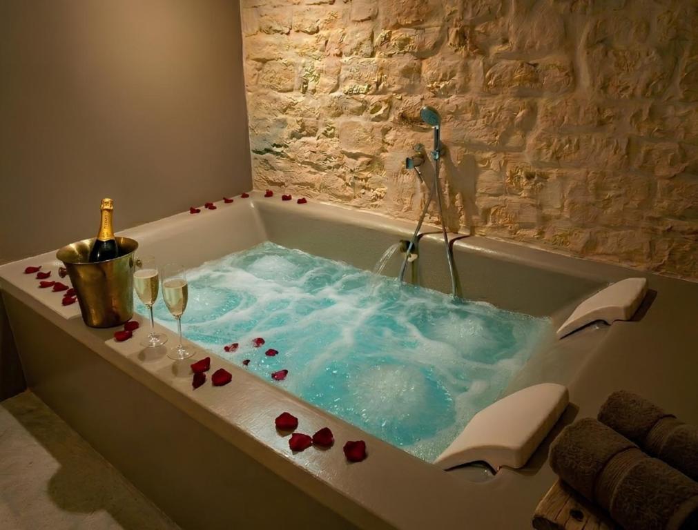 a bath tub with wine glasses and a bottle of champagne at Suite Dimora Antico Campanile in Locorotondo