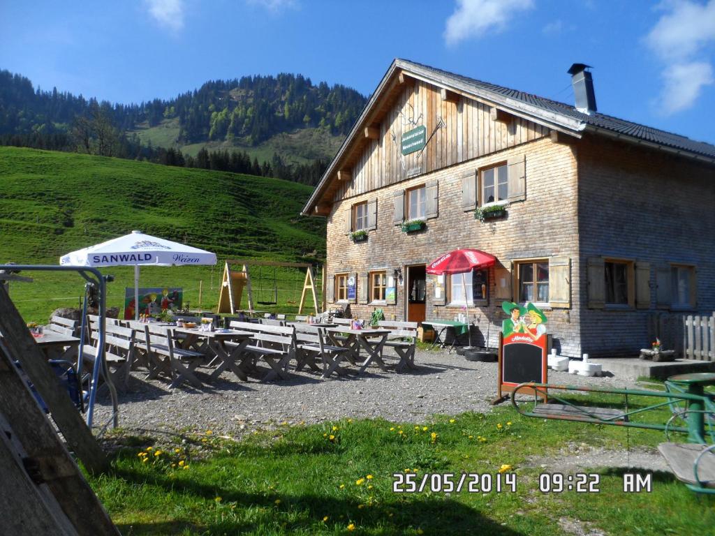 a building with picnic tables in front of it at Jausenstation Neuschwand in Hittisau