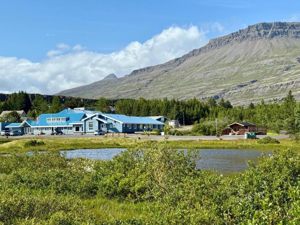 Ein großes blaues Gebäude vor einem Berg im Hintergrund in der Unterkunft Hotel Breiddalsvik in Breiðdalsvík