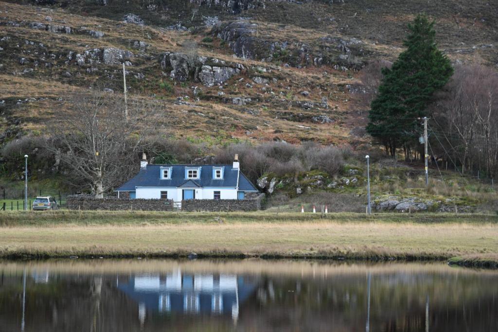 a house on the shore of a body of water at Kathleen's Croft, charming detached croft house in Torridon