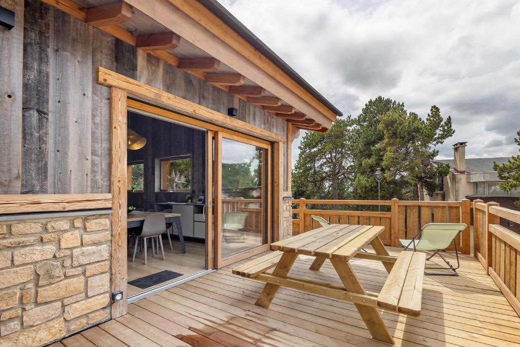 a wooden deck with a wooden picnic table on a building at Chalet nid des écureuils in Font-Romeu-Odeillo-Via