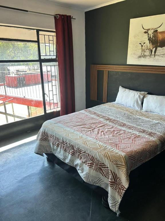 a bedroom with a bed with a bull on the wall at Miners Rest Lodge in Phalaborwa