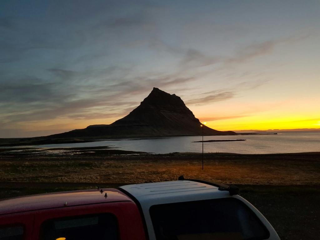 a truck parked in front of a mountain at sunset at Kirkjufell View Cottages in Grundarfjordur