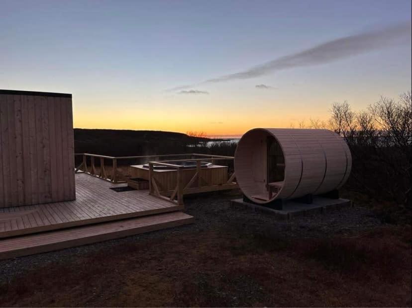 Ein rundes Gebäude auf einer Terrasse mit dem Sonnenuntergang im Hintergrund in der Unterkunft Hotel Hafnarfjall in Borgarnes