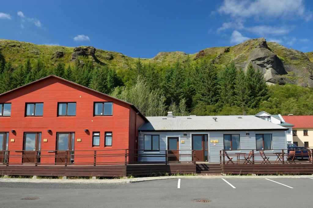 a large red building with a mountain in the background at Klausturhof Guesthouse in Kirkjubæjarklaustur