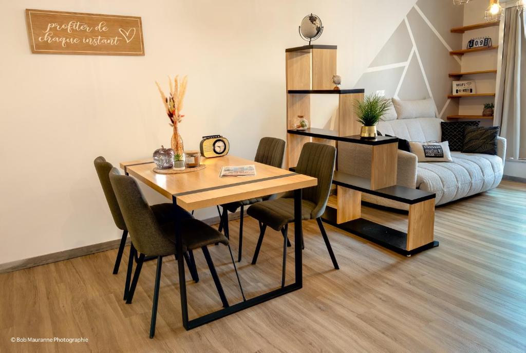 a dining room with a table and chairs and a couch at L'Escapade Pannessac troisième étage in Le Puy-en-Velay