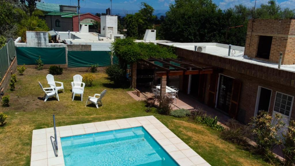 a backyard with a pool and chairs and a house at El descanso - Costa Azul in Villa Carlos Paz