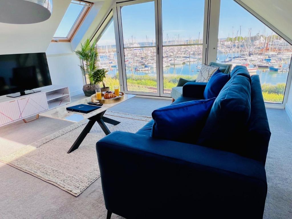 a living room with a blue couch and a large window at Island Point Horizon View in Lymington