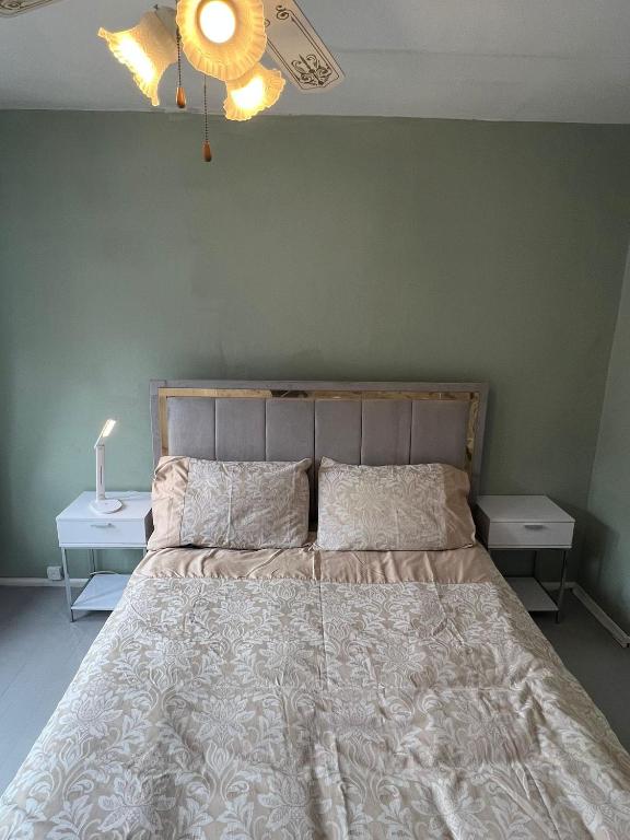 a bedroom with a large bed with two night stands at Spacious King En Suite in St. Albans