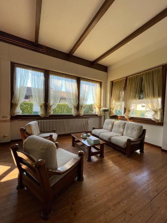 a living room with couches and chairs and windows at Casa dell'OCA in Viganò
