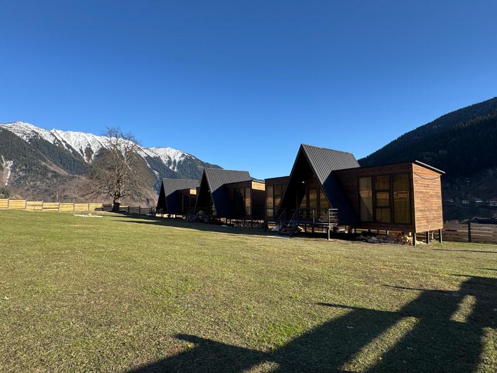 a group of buildings in a field with mountains in the background at Panorama Mazeri in Tvebishi
