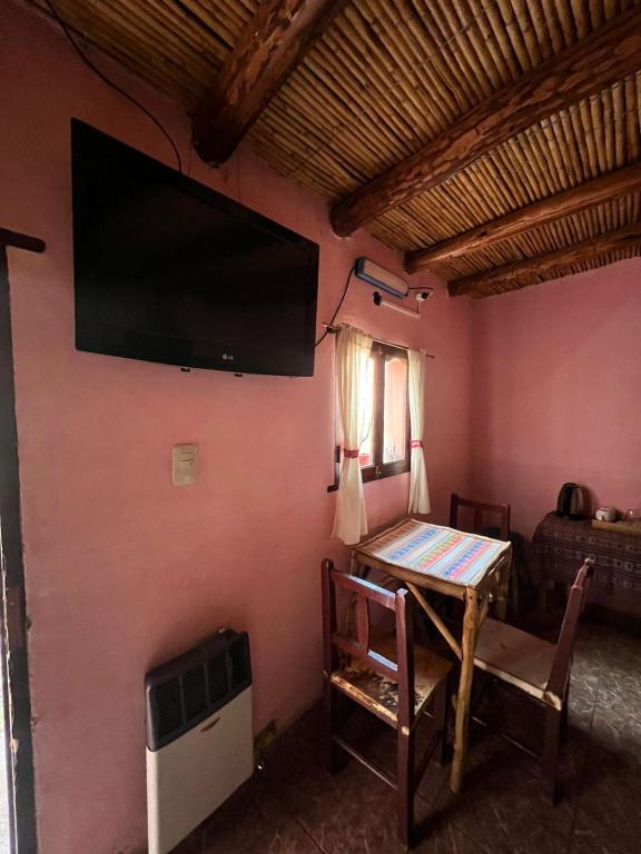 a room with a table and a tv on a wall at Kantuta Hospedaje in Tilcara