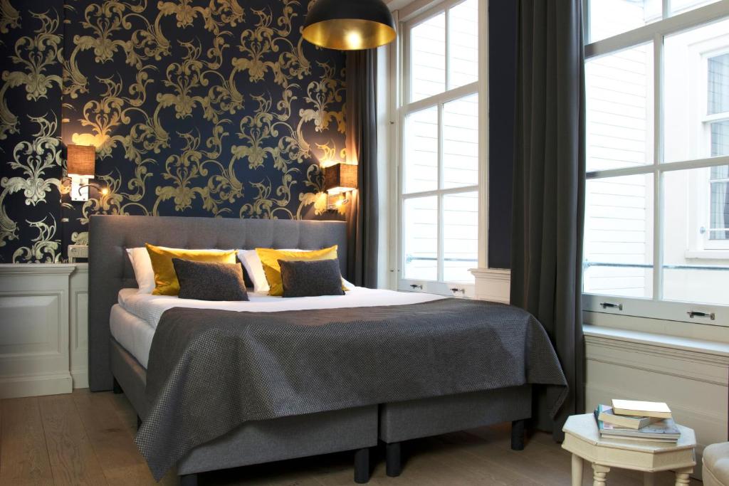 a bedroom with a bed with a black and gold wallpaper at Grand Canal Boutique Hotel in Amsterdam