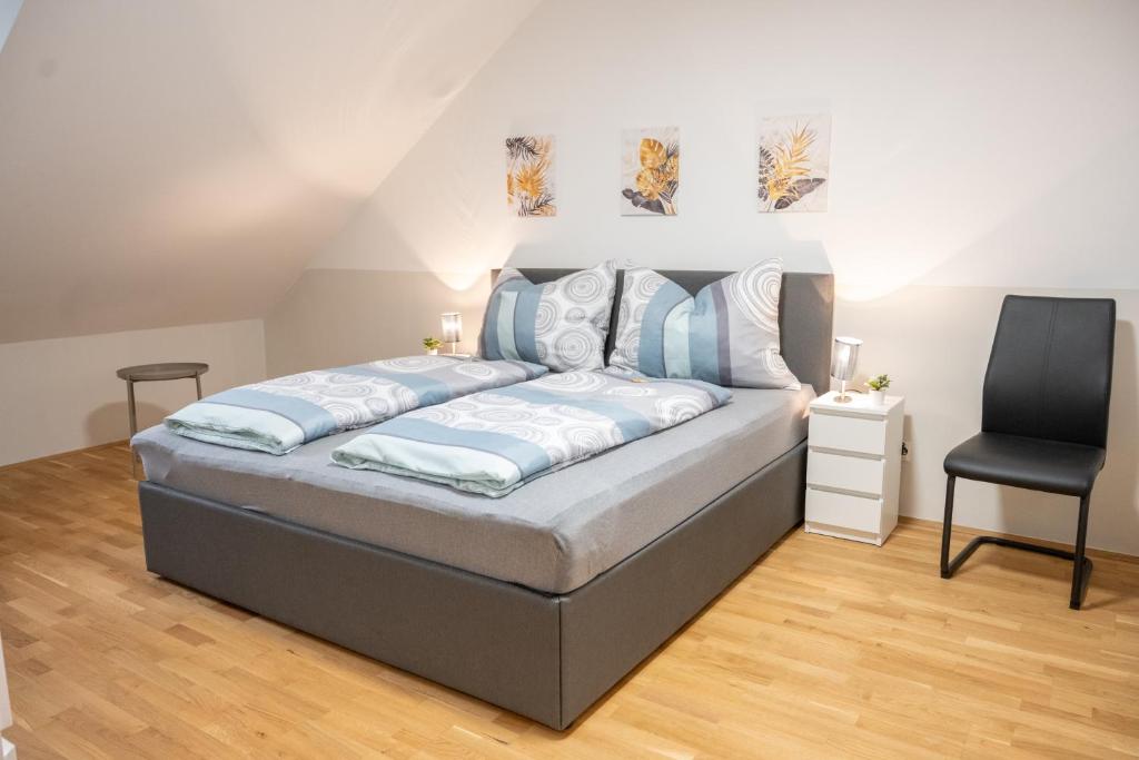 a bedroom with a bed and a black chair at Paky Appartements 00317 in Bruck an der Leitha