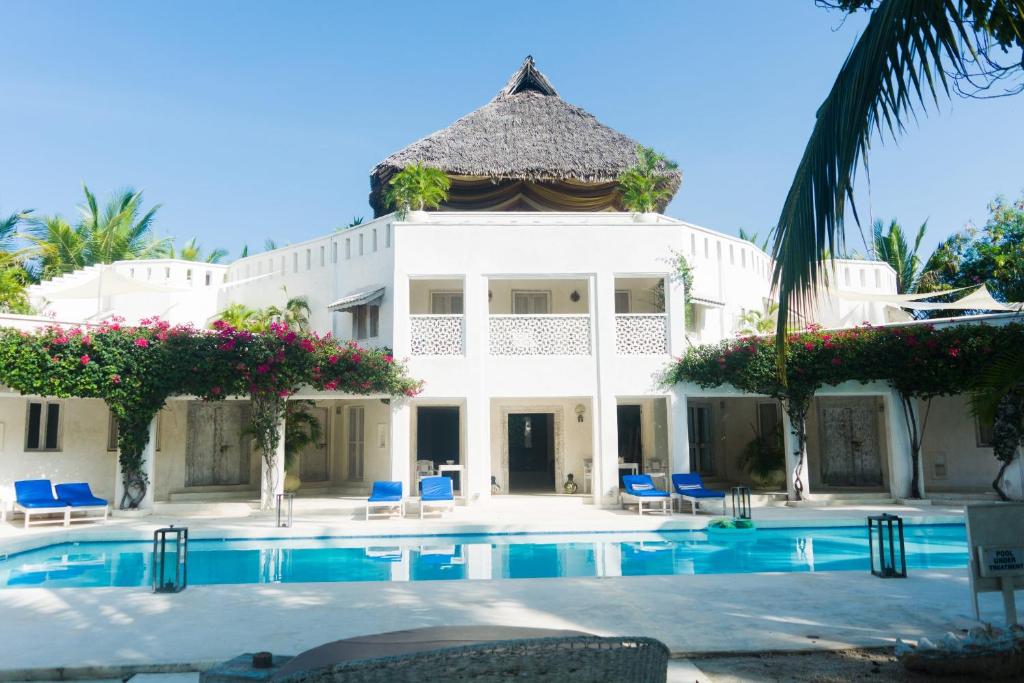 a large white house with a swimming pool at The Villa Luxury Suites Hotel in Diani Beach