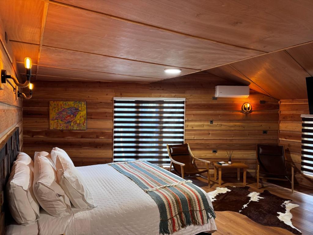 a bedroom with wooden walls and a bed and a table at Hotel Boutique La Casa de Coco in Gorbea