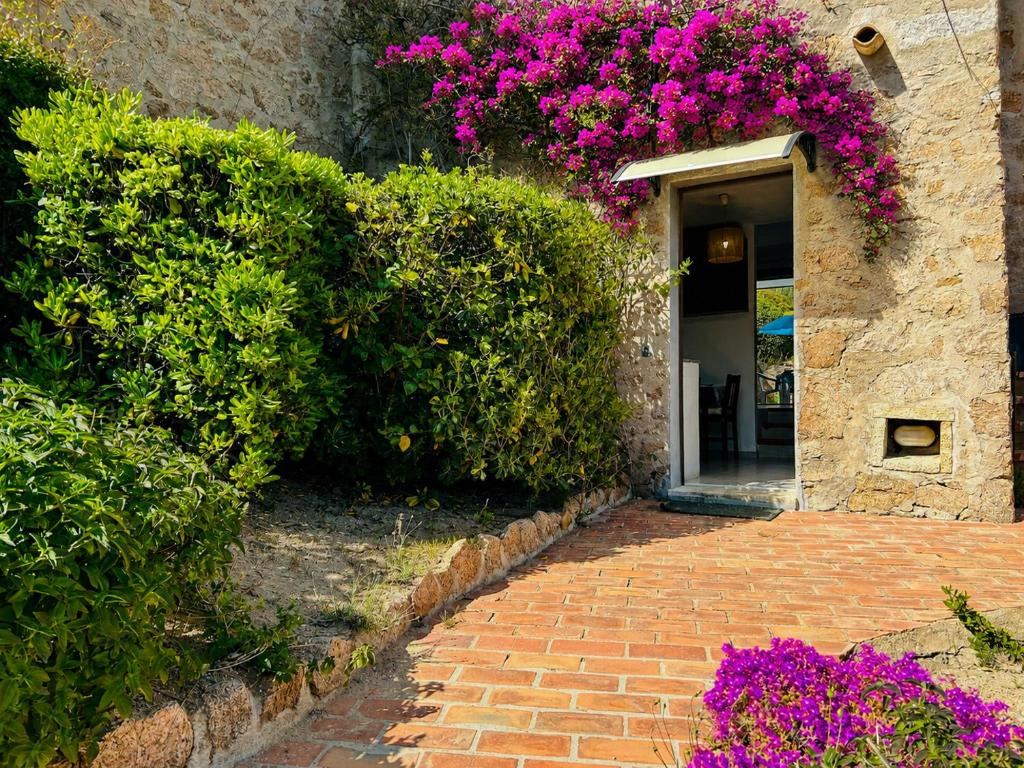 a brick walkway leading to a door with purple flowers at Baja Sardinia CB 1 with Pool 100m from the Beach in Baja Sardinia