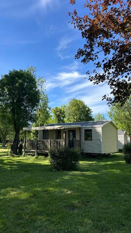 a small white house with a porch on a lawn at Camping le Martin Pêcheur in Magné