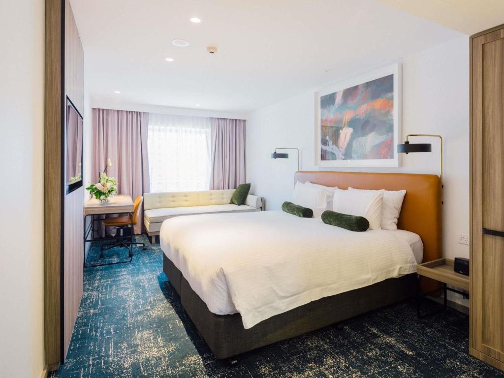 a hotel room with a large bed and a desk at Novotel Sydney Darling Square in Sydney