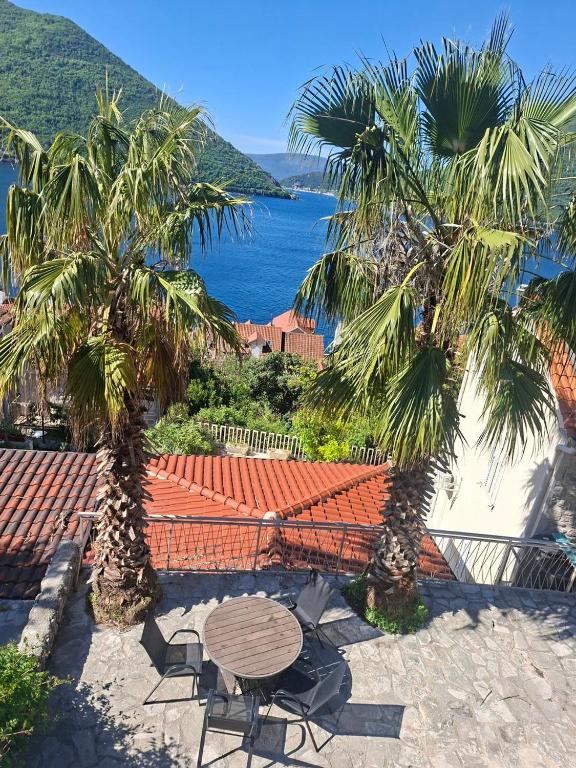 a patio with a table and chairs and palm trees at Apartman Perast in Perast
