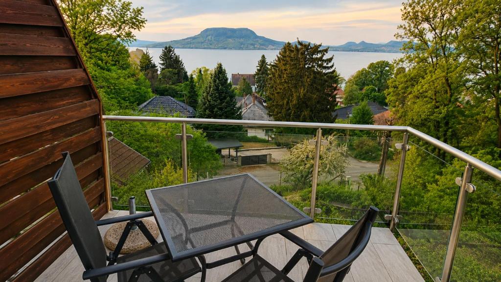 a glass table and chairs on a balcony with a view at Hilltop Apartments in Fonyód